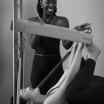 Pilates instructor guiding two clients on reformers