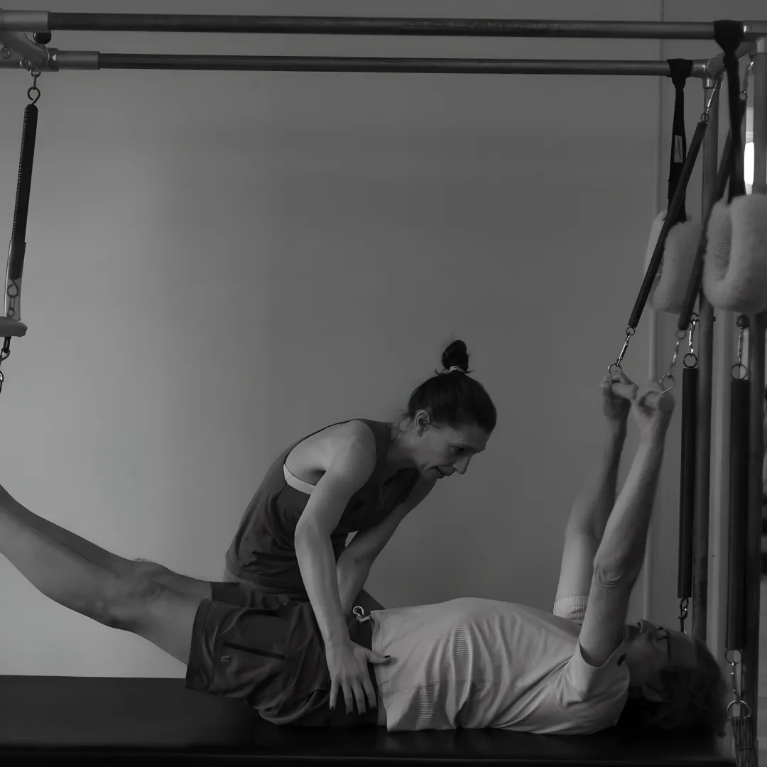 Instructor explaining reformer setup to a beginner Pilates client