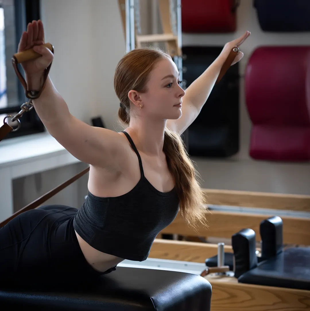 Instructor guiding a beginner on a Pilates reformer