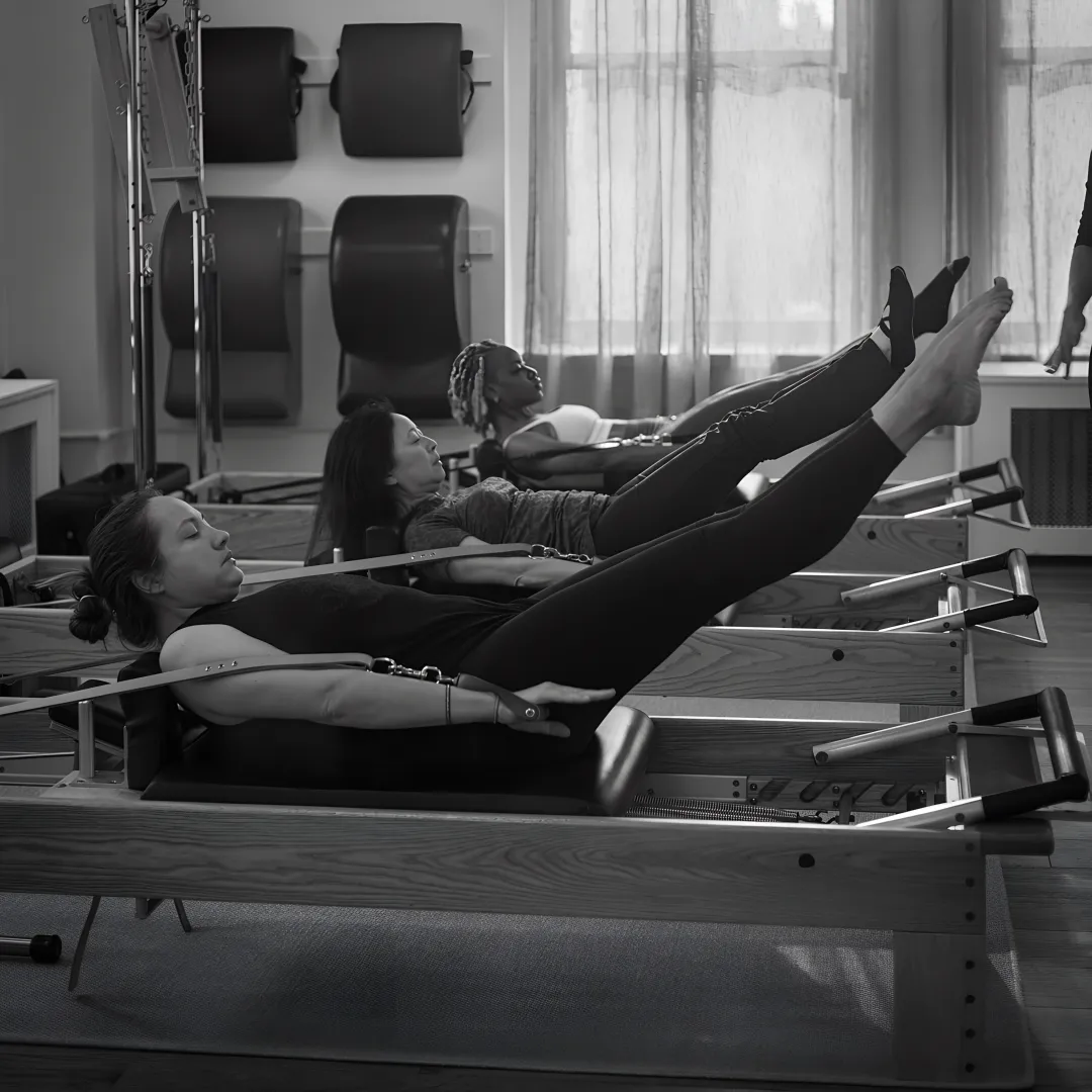 Instructor guiding a client on a Pilates reformer