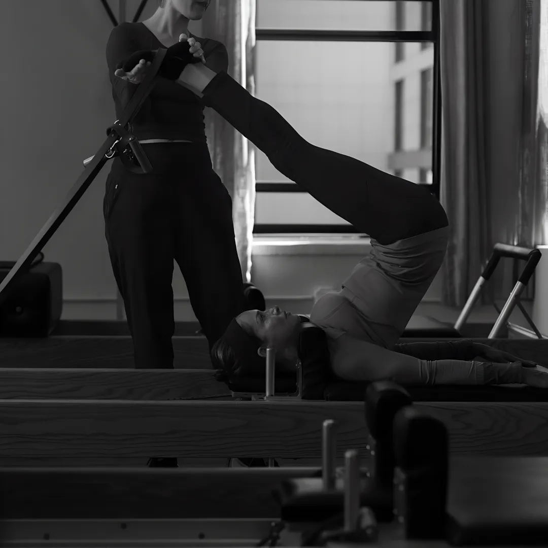 Instructor guiding a Reformer Pilates session in a boutique studio