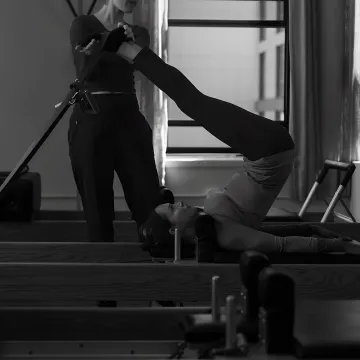 Instructor guiding a Reformer Pilates session in a boutique studio