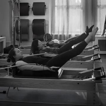 Instructor guiding a reformer Pilates session in a boutique studio