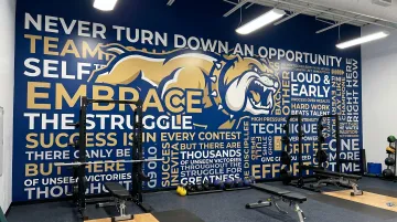 Custom large-format wall mural with team mascot colors and motivational branding in gymnasium