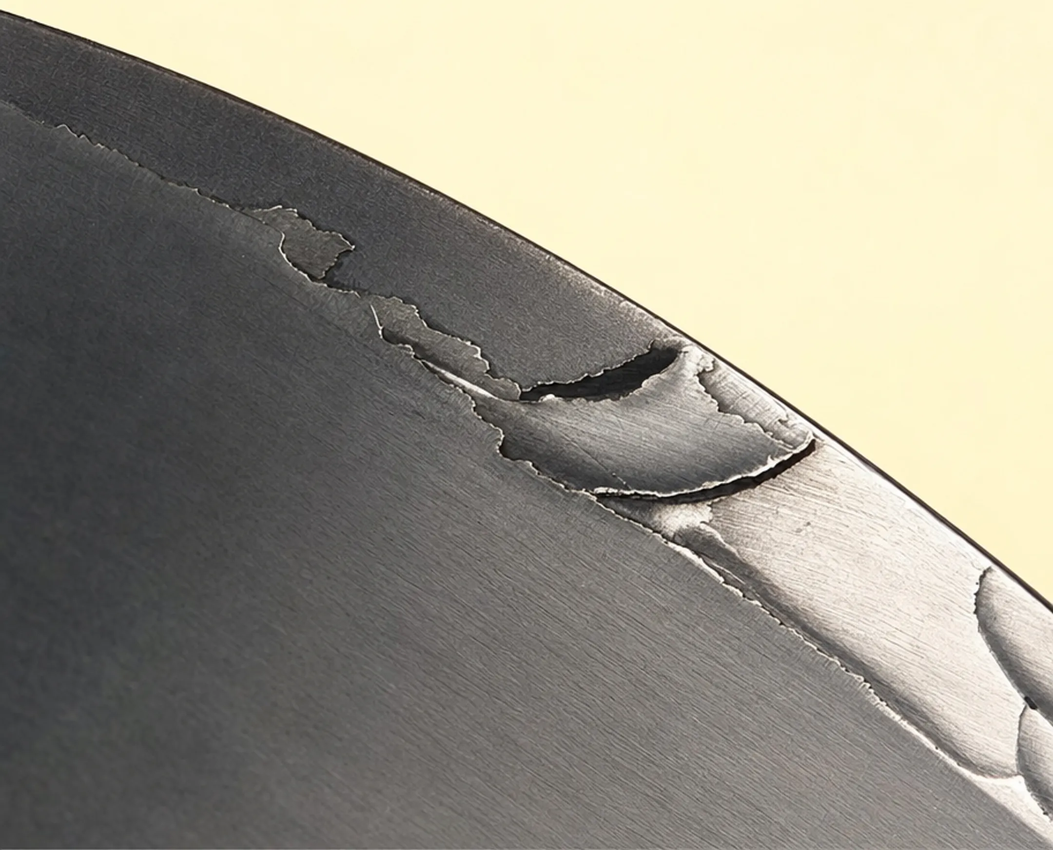 Close-up of peeling coating failure on industrial mold tooling surface