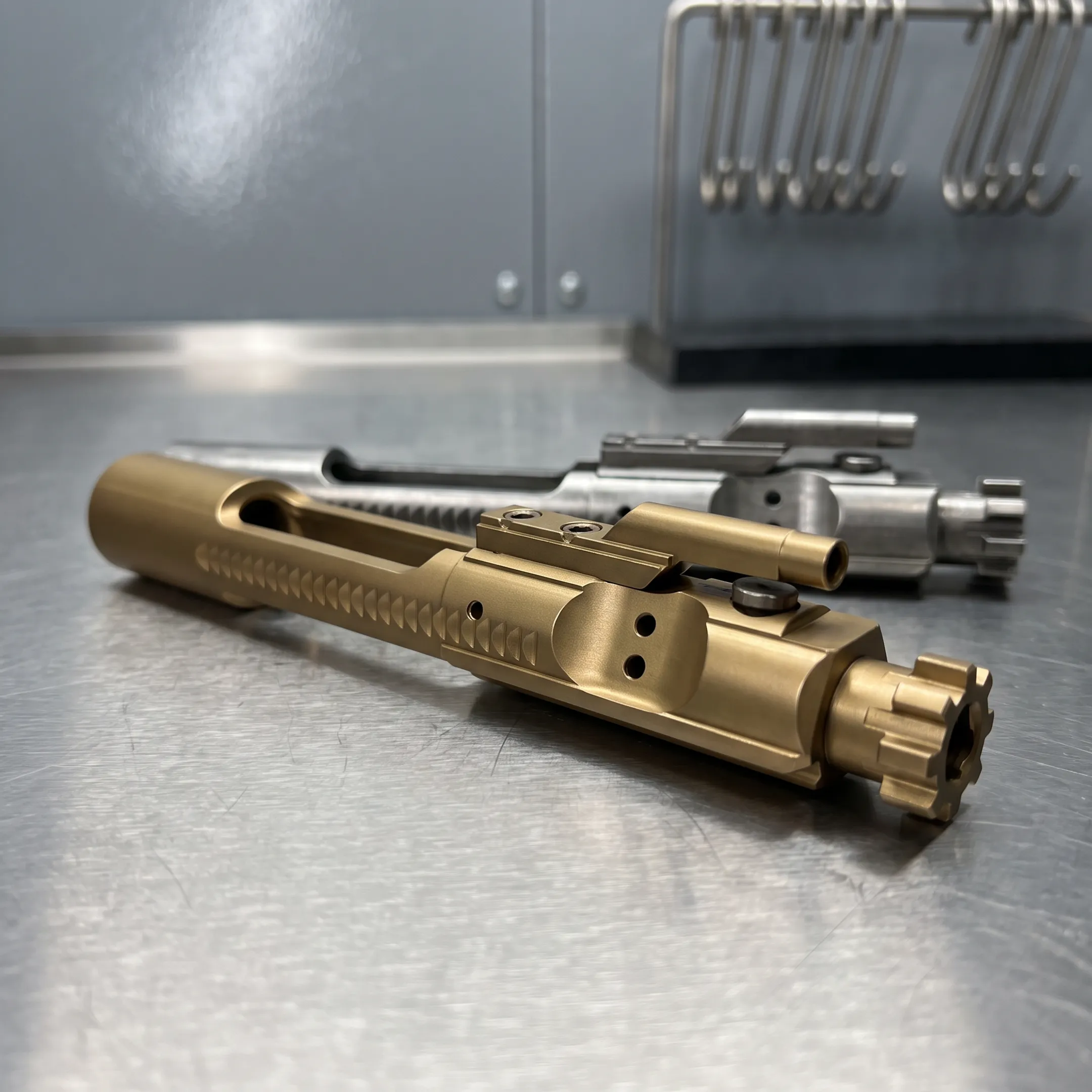 Gold-finished PVD-coated bolt carrier group on a clean workshop surface