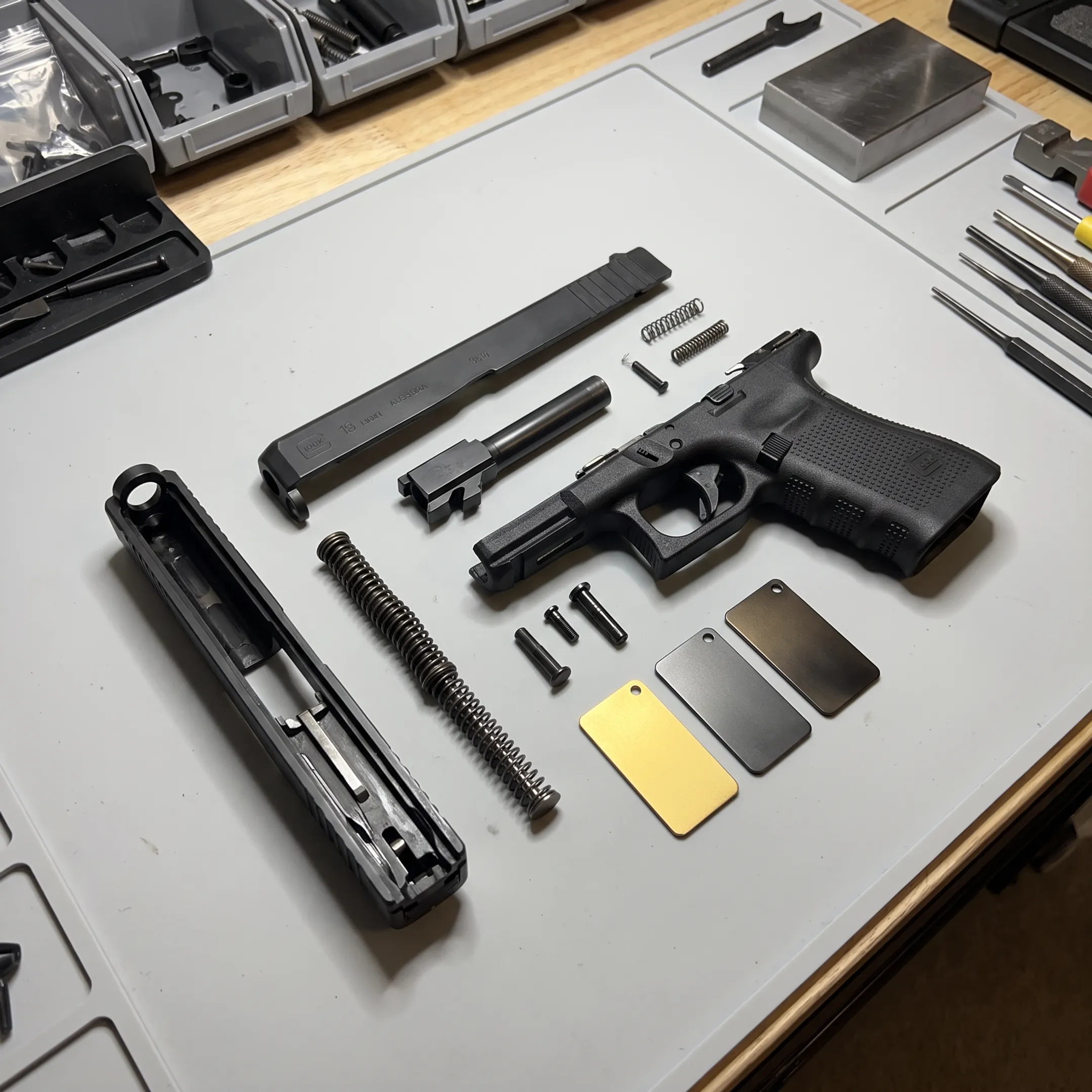 Glock slide and firearm components displayed beside coated metal samples