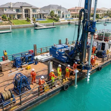 Seawall installation using waterside helical pile technology with crane and specialized marine equipment