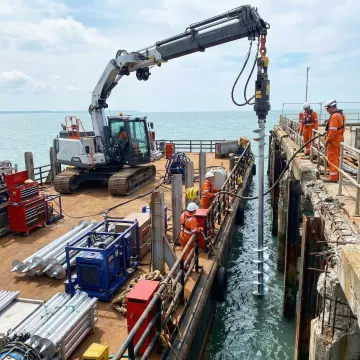 Advanced helical pile installation equipment working on marine pier foundation