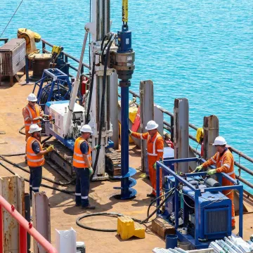 Helical marine piles being installed in coastal waters with specialized equipment