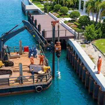 Waterside seawall installation equipment working near residential dock