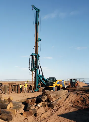 Industrial drilling rig installing grouted pile foundation system on construction site