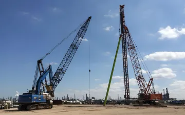 Professional piling contractors installing helical piles with specialized equipment on industrial construction site