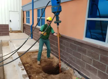 Industrial foundation repair crew installing helical piles at petrochemical facility