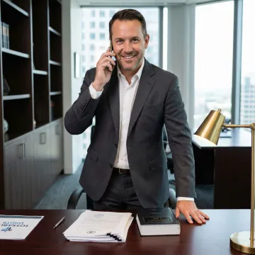 Legal professional reviewing case files while on phone call in modern law office