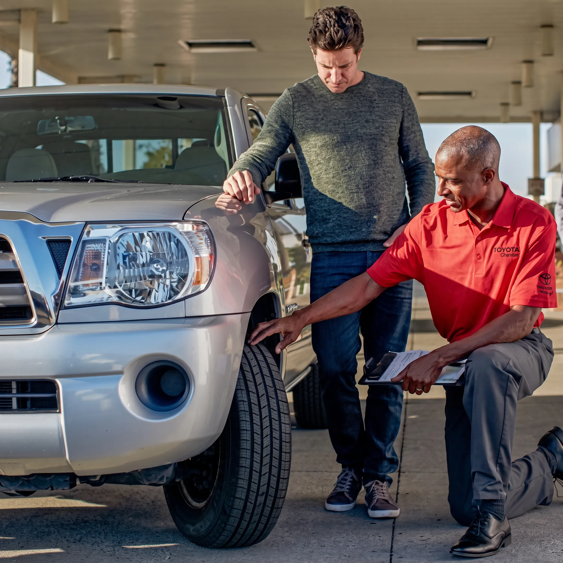 Toyota technician inspecting a damaged tire beside a roadside vehicle