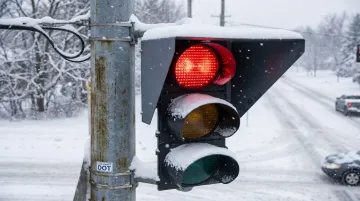 Snow-proof visor installed on red traffic signal lens in winter conditions