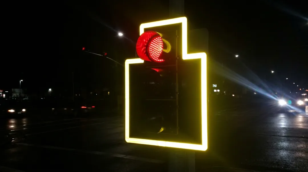 Illuminated retroreflective traffic signal backplate glowing at nighttime intersection