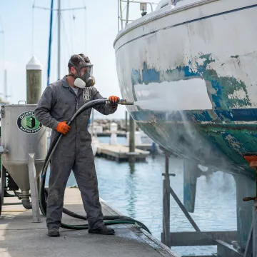 Professional dustless blasting service being performed on a boat hull in Tampa Bay