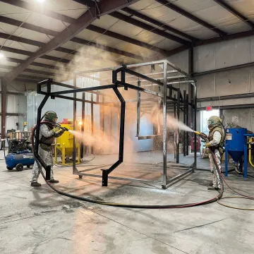 Industrial blast cleaning equipment preparing metal surface for coating application