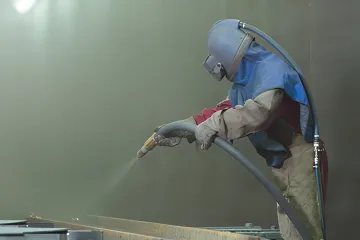 Industrial abrasive blasting equipment preparing metal surface in Tampa Bay facility