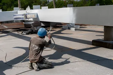 Technician applying powder coating finish to metal component
