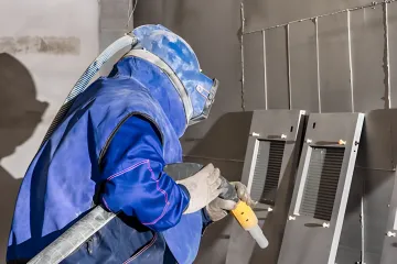 Professional bead blasting equipment preparing metal surface in Tampa Bay facility