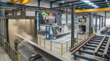 Industrial shot blasting equipment processing large structural steel beams in shop facility