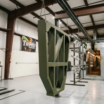 Powder coated defense component on production rack