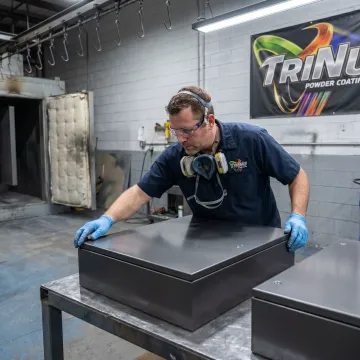 Technician inspecting coated electrical enclosure