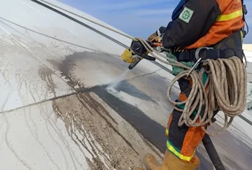 Industrial technician performing quality blast cleaning on metal component