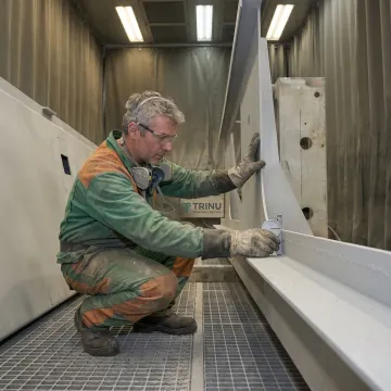 Technician inspecting blasted marine metal parts