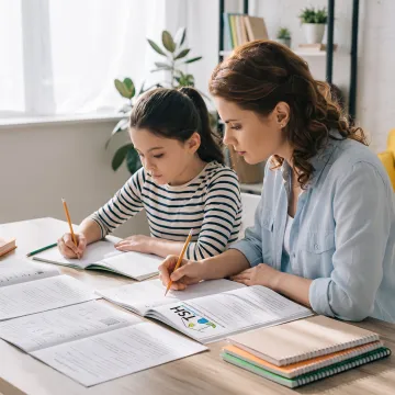 Parent guiding a child through a homeschool writing lesson