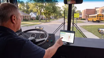 School bus driver using modern navigation and route management technology in vehicle cab