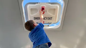 Young elementary student attempting to operate school bus roof emergency hatch