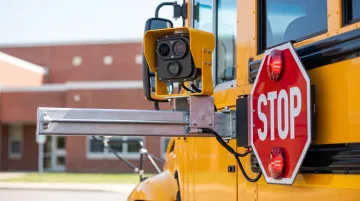 School bus exterior stop-arm camera system mounted near driver-side door