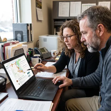 Transportation staff reviewing school bus routes on a laptop during onboarding