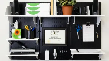 Pegboard wall organizer with hooks cups shelves and mesh pouches in office workspace