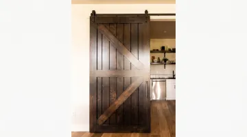 Rustic sliding barn door on walk-in kitchen pantry with dark hardware
