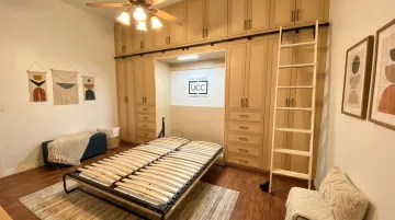 Murphy bed integrated into custom built-in basement cabinetry with flanking storage cabinets