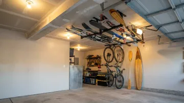 Wall-mounted vertical bike and ski storage rack system in organized garage or basement