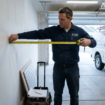 Installer measuring garage wall for storage panels