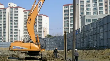 Impact pile driver operating near residential structure at active urban construction site
