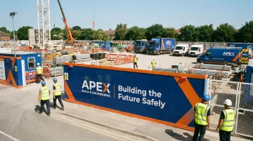 Branded construction site hoarding safety helmets and company vehicles on active project site