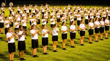 High school marching band rehearsing on football field during practice session
