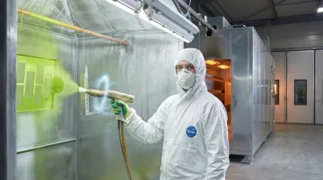 Industrial powder coating process showing electrostatic spray gun applying polymer coating to aluminum part