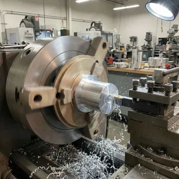 Precision aluminum custom part being machined on a CNC lathe in an industrial workshop