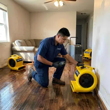 Water damage technician drying a flooded room