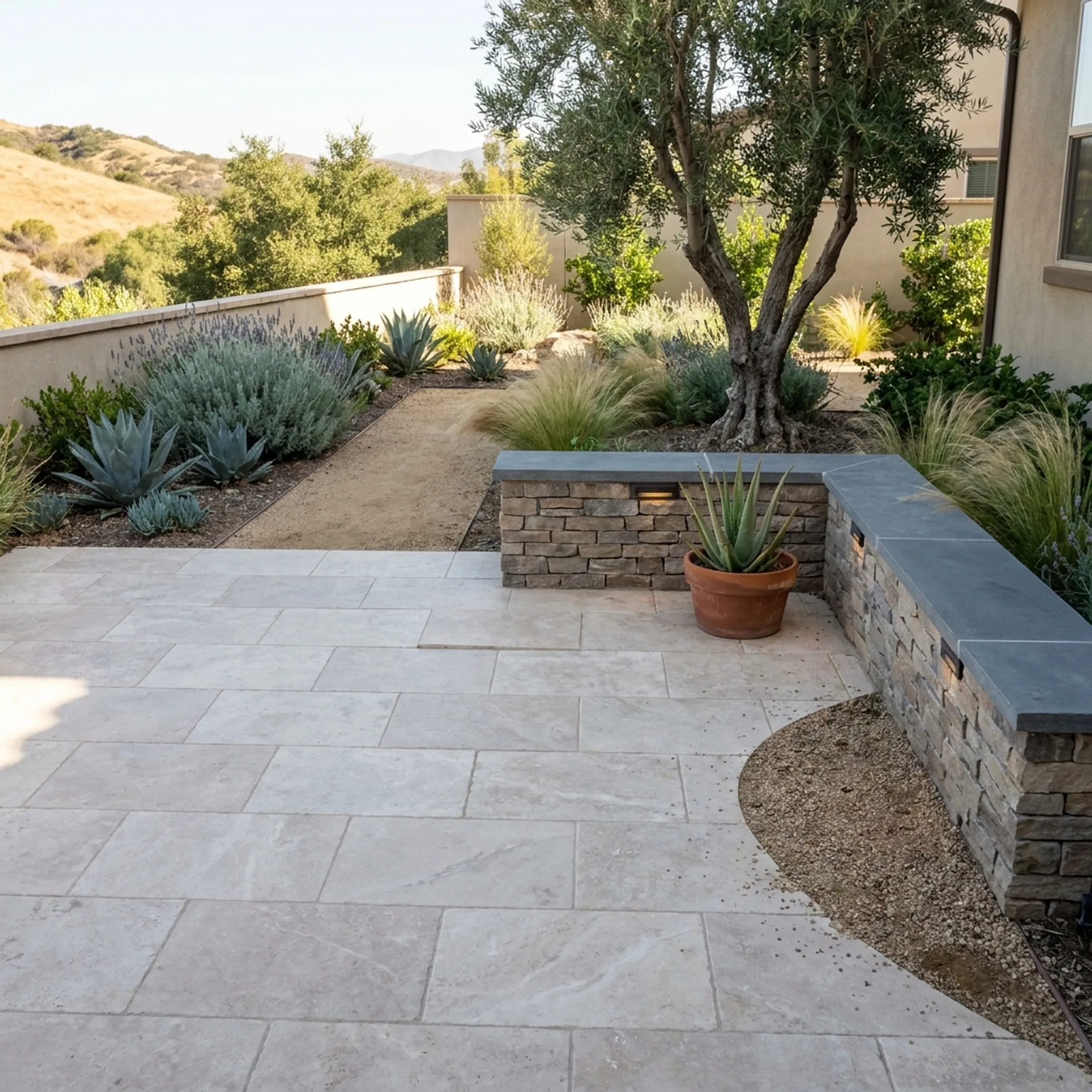 Completed residential hardscape patio with stone pavers and drought-tolerant landscape