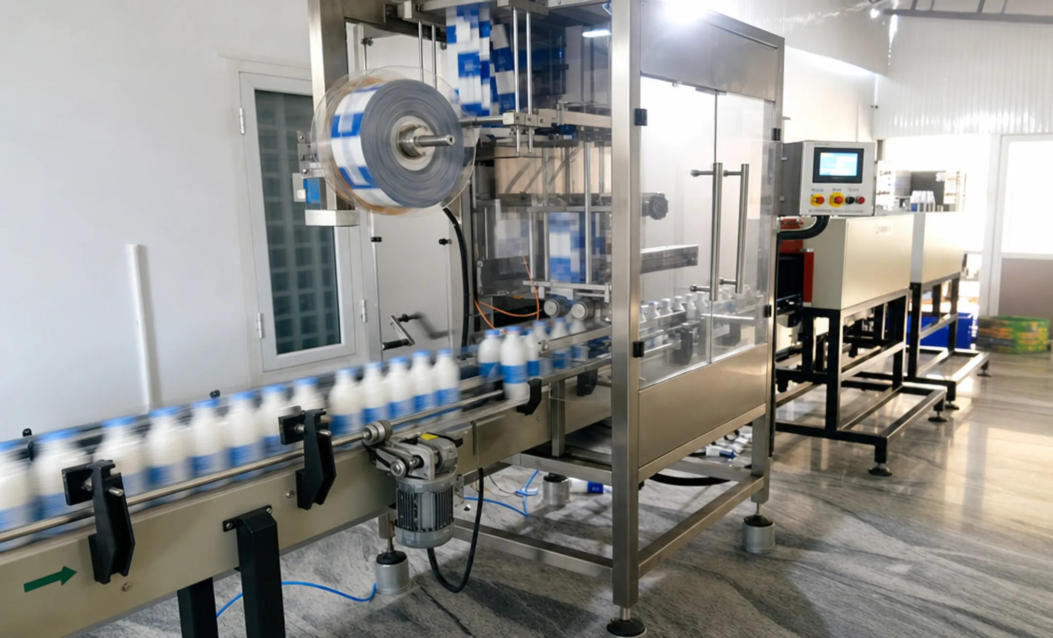High-speed shrink sleeve applicator machine running bottles on conveyor line